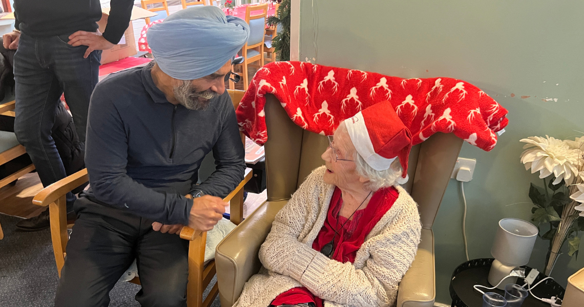 Leader of Redbridge Council, Cllr Jas Athwal, speaking to an elderly woman at a care home