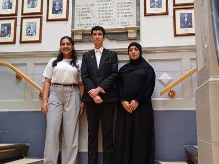 Three Members of Youth Parliament for Redbridge standing in front of pictures of previous Redbridge Mayors