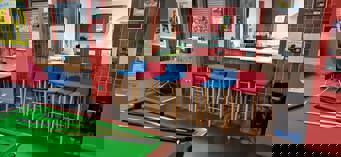 Inside the main room at Hainault Youth Centre looking through the hatch into the kitchen. Red and blue high chairs in front of the hatch