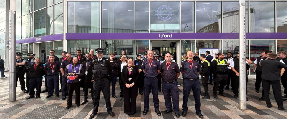 A diverse group of people stands together in front of a large building, smiling and engaging with one another.